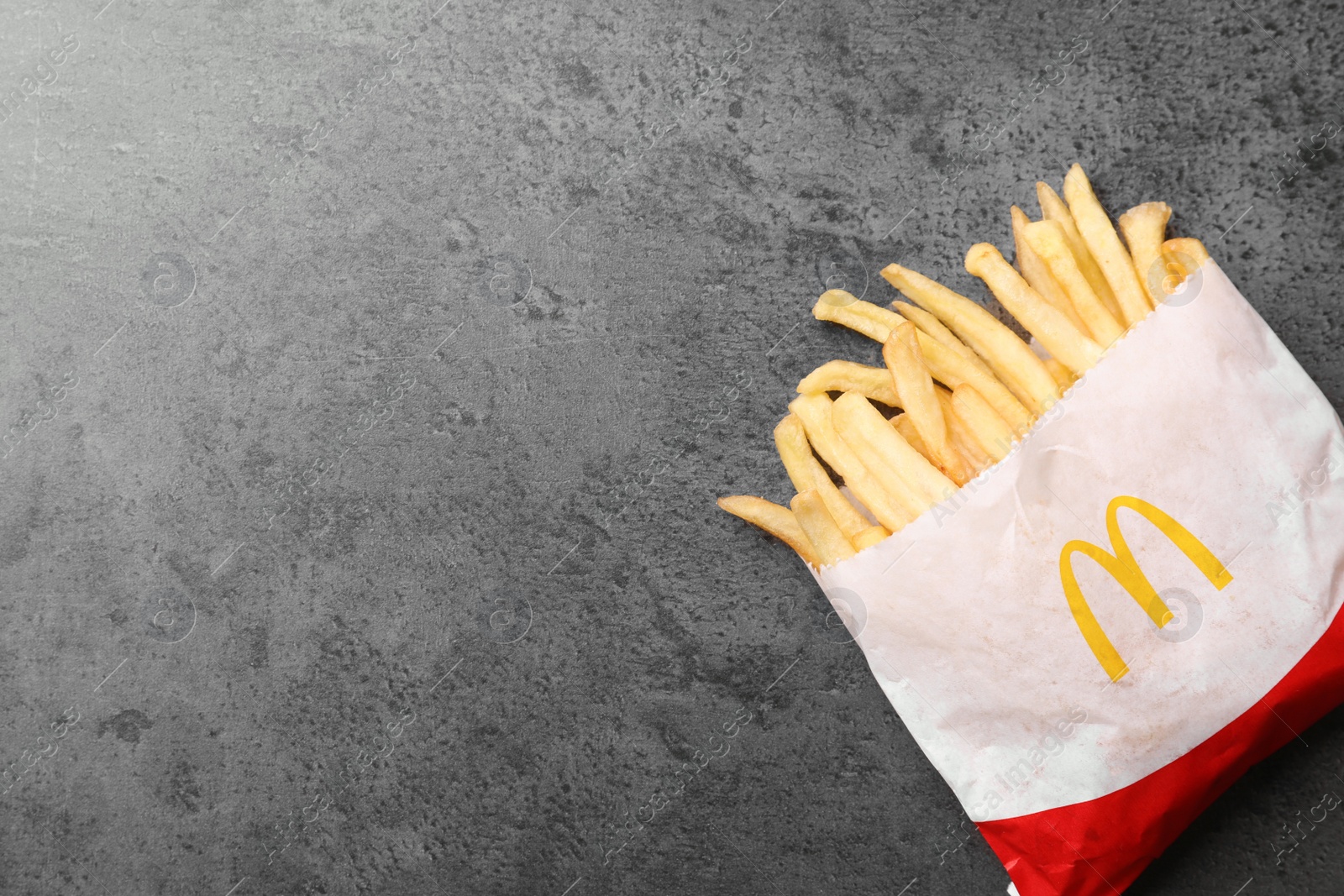 Photo of MYKOLAIV, UKRAINE - AUGUST 12, 2021: Small portion of McDonald's French fries on grey table, top view. Space for text