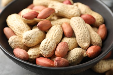 Photo of Fresh unpeeled peanuts in bowl on table, closeup