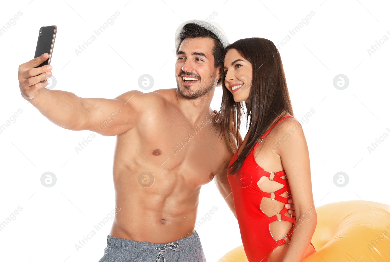 Photo of Young attractive couple in beachwear with inflatable ring taking selfie on white background