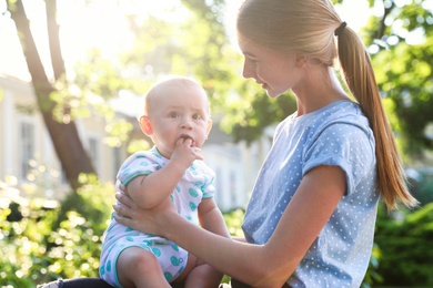 Teen nanny with cute baby outdoors on sunny day