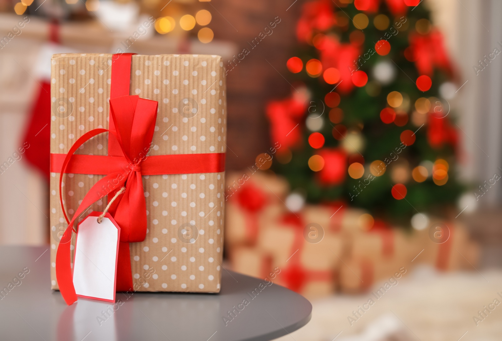 Photo of Gift box on table and Christmas tree in room