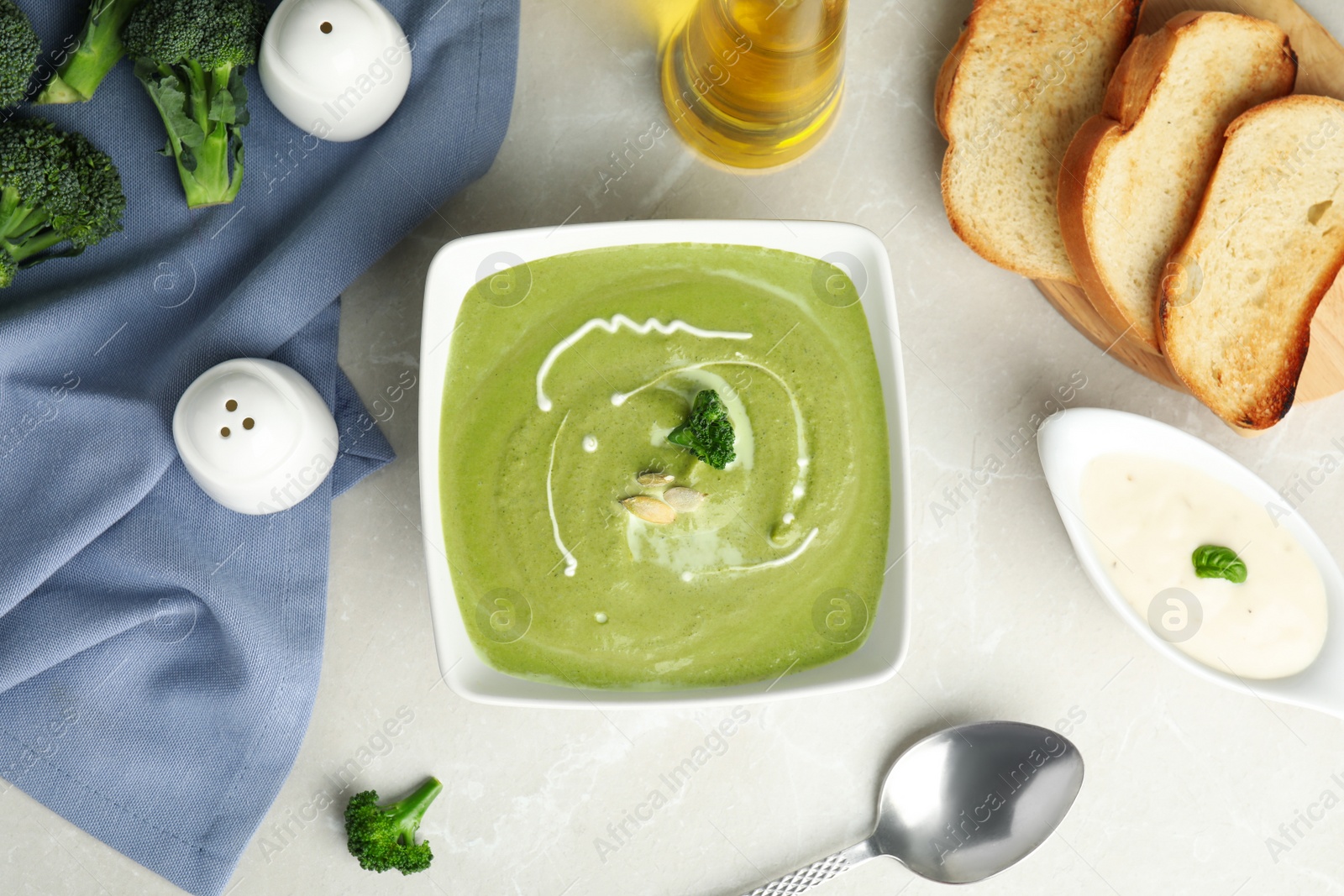 Photo of Delicious broccoli cream soup served on grey marble table, flat lay