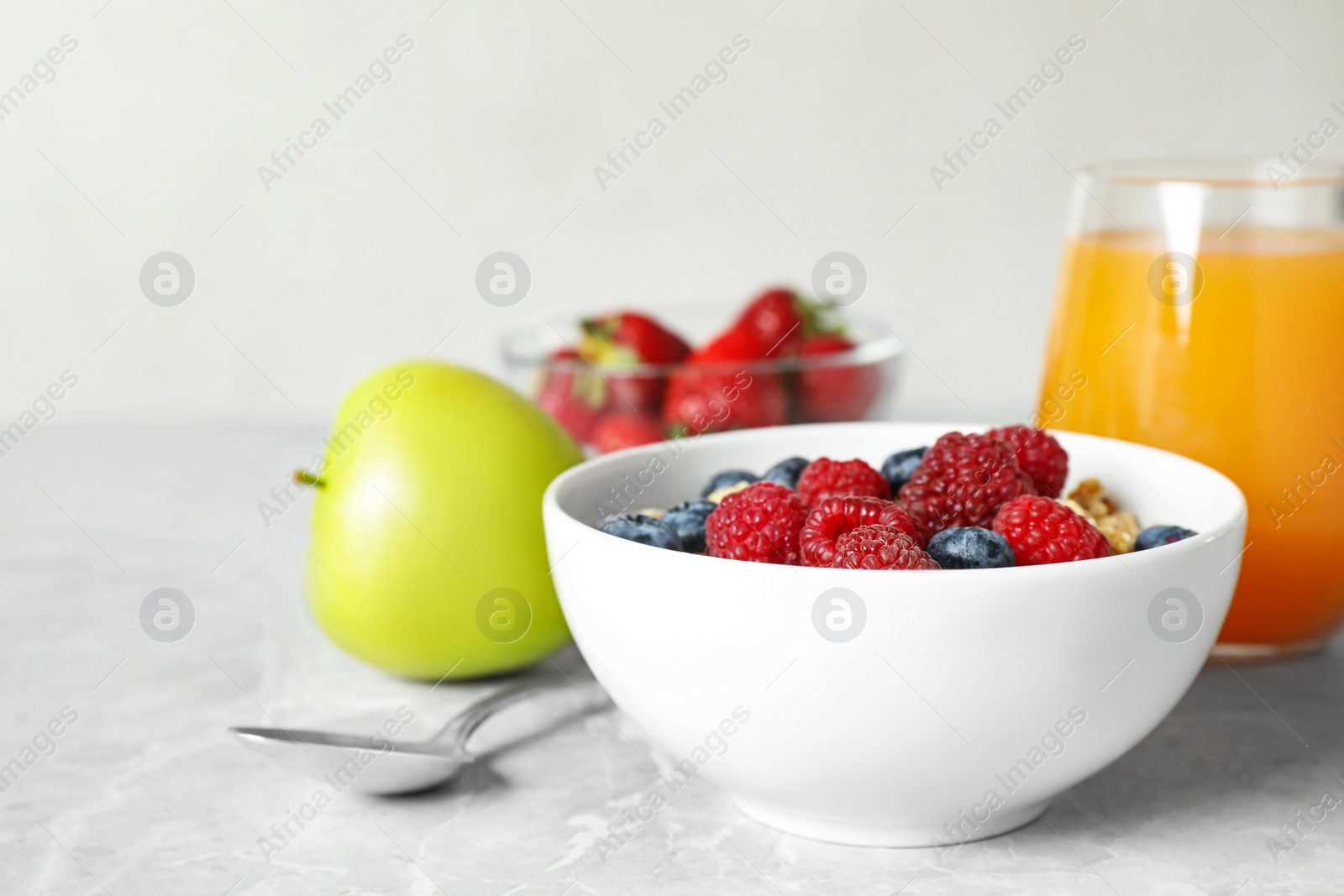 Photo of Healthy breakfast with granola and berries on light grey marble table