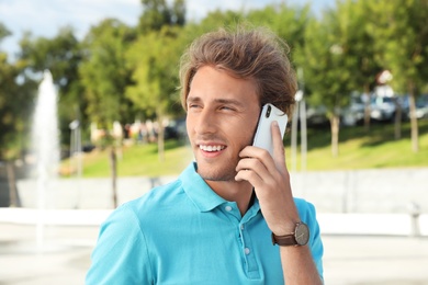 Portrait of handsome young man talking on phone outdoors