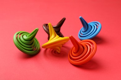 Photo of Many colorful spinning tops on red background, closeup