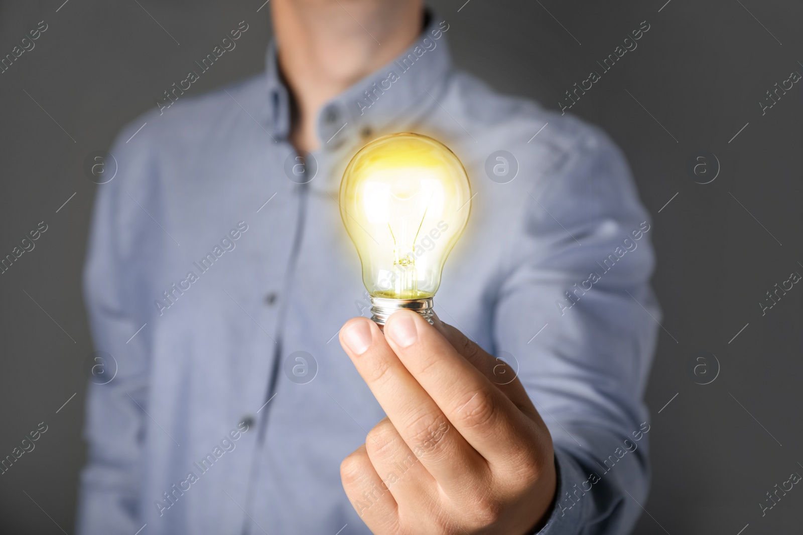 Image of Glow up your ideas. Man holding light bulb on grey background, closeup