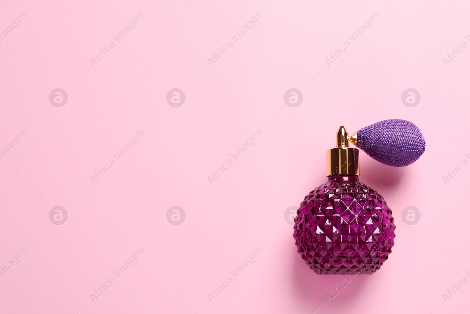 Photo of Bottle of perfume and space for text on pink background, top view