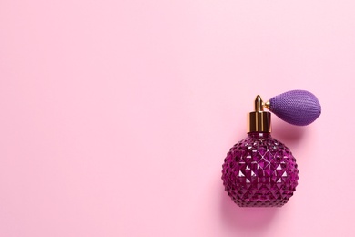 Bottle of perfume and space for text on pink background, top view