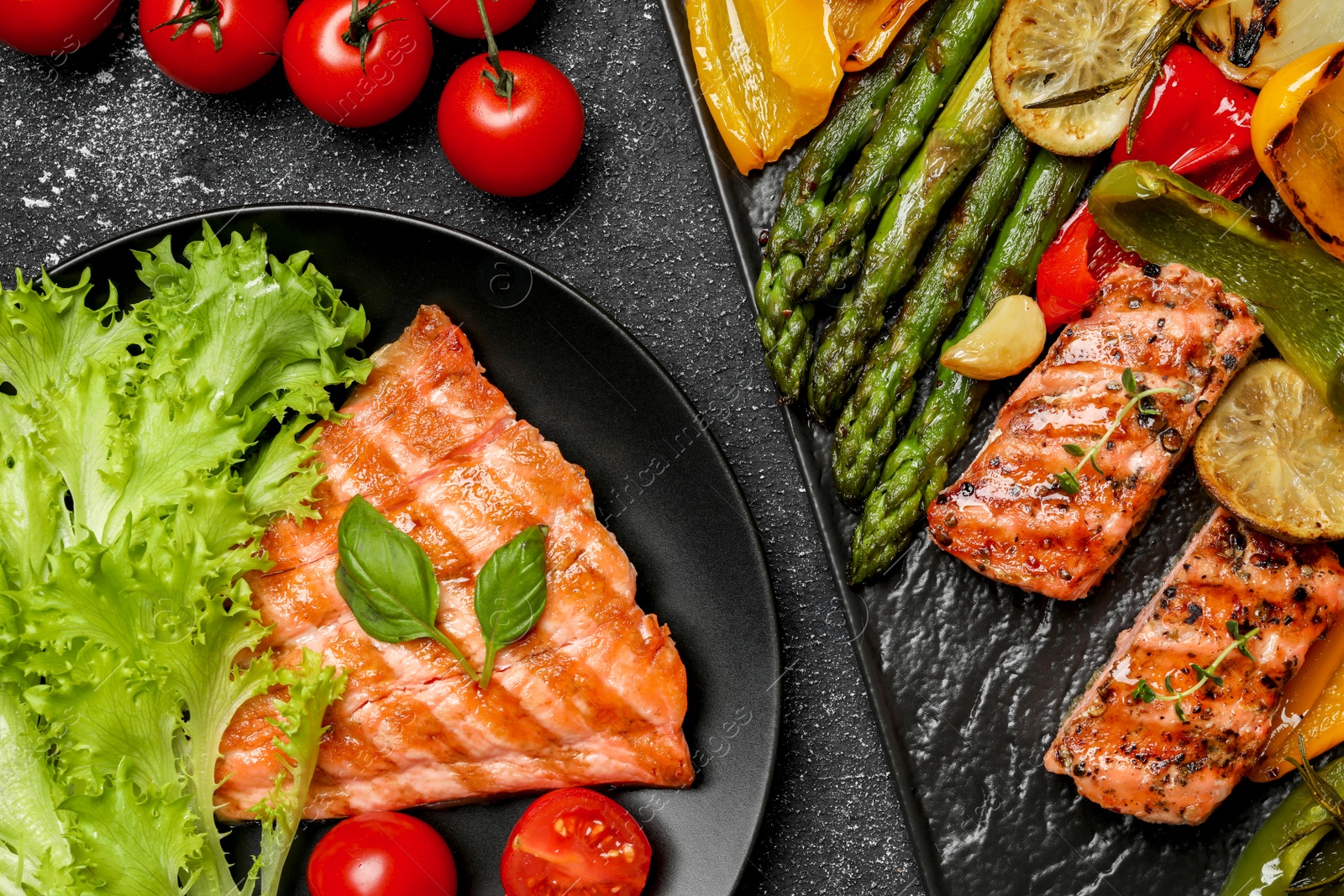 Photo of Tasty cooked salmon with fresh and grilled vegetables on black table, flat lay