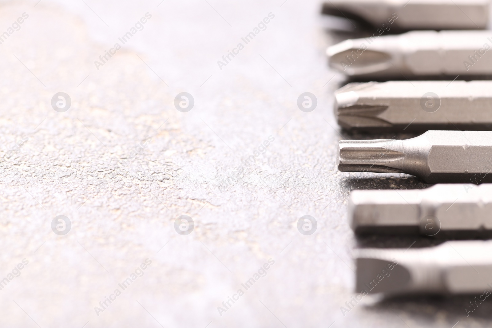 Photo of Different screwdriver bits on grey table, closeup. Space for text