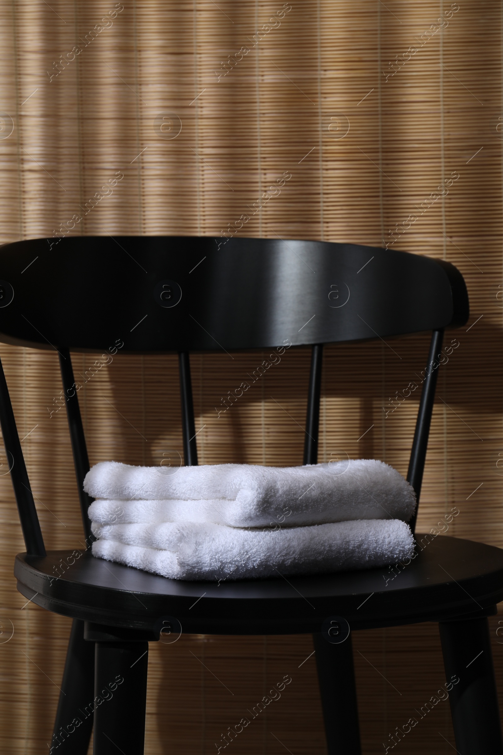 Photo of Stacked soft towels on black chair indoors