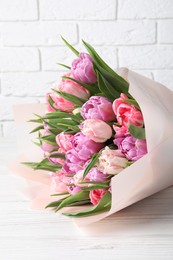 Photo of Bouquet of beautiful tulips on white wooden table, closeup