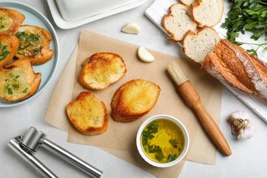 Photo of Slices of delicious toasted bread with garlic on light marble table, flat lay