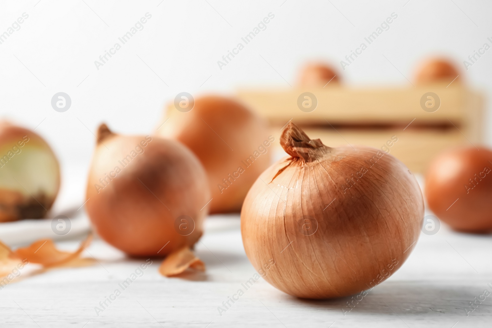 Photo of Ripe yellow onion bulbs on white wooden table, closeup