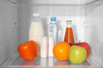 Photo of Different products on shelf inside modern refrigerator