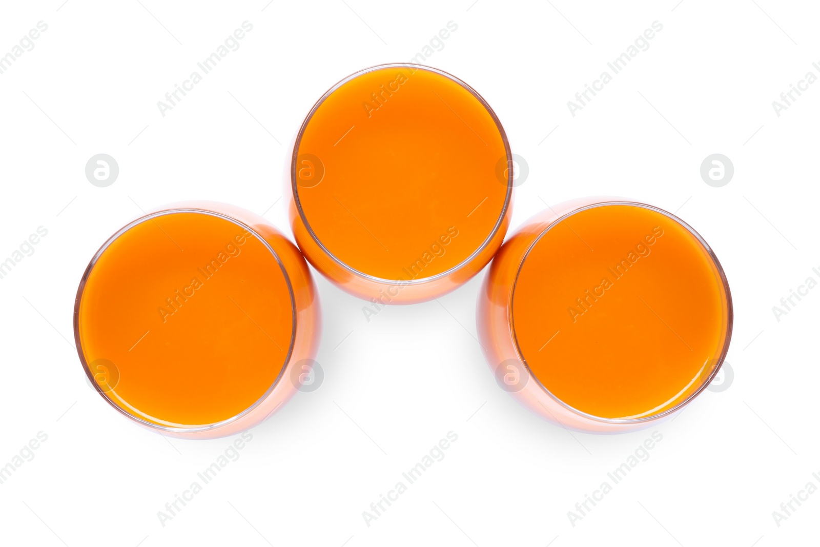 Photo of Three glasses of fresh carrot juice on white background, top view