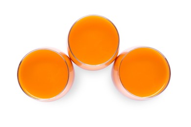 Photo of Three glasses of fresh carrot juice on white background, top view