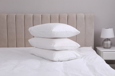 White soft pillows on bed and lamp in room