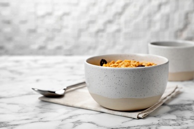 Photo of Bowl with whole grain cereal and raisins on marble table