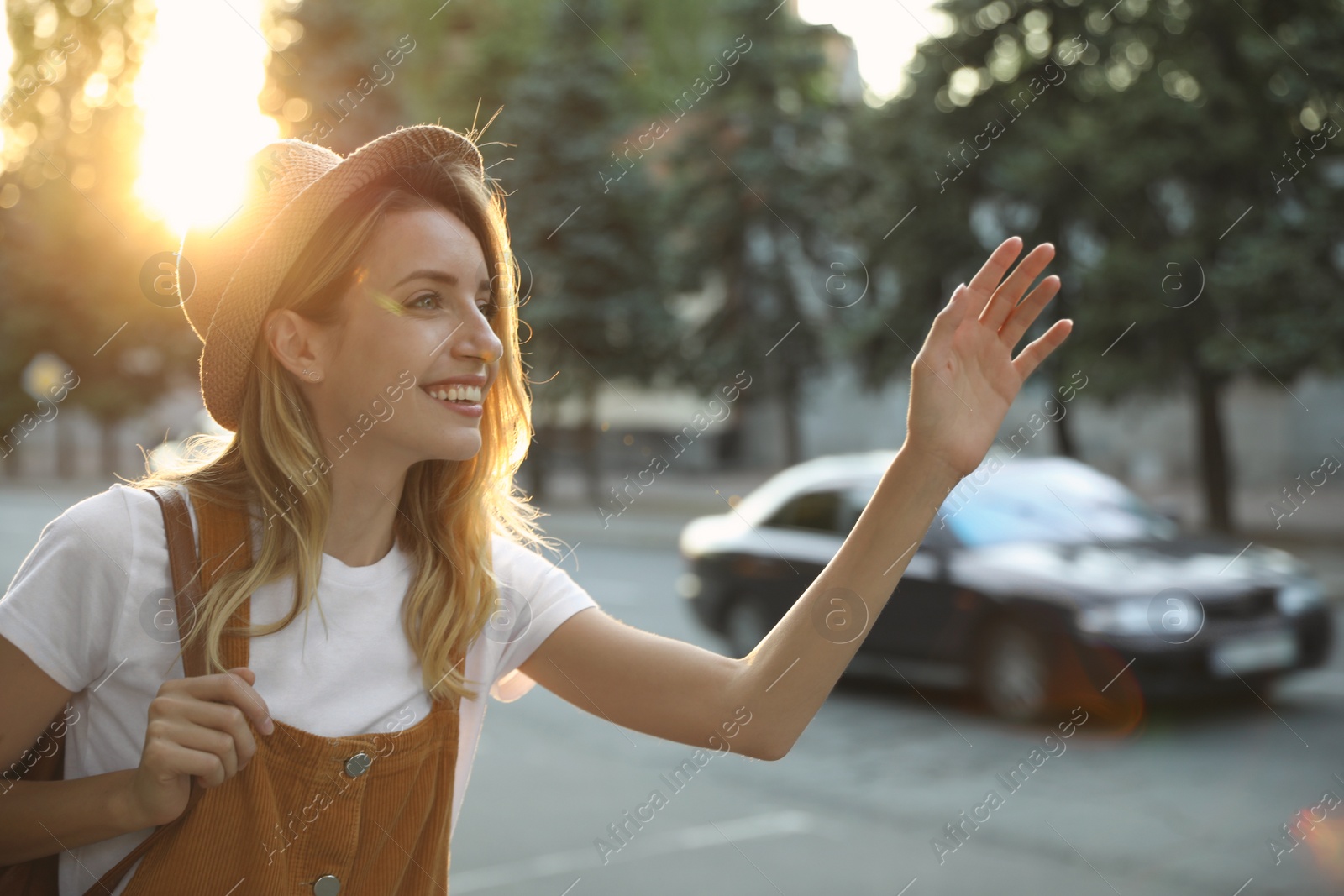 Photo of Young woman catching taxi on city street