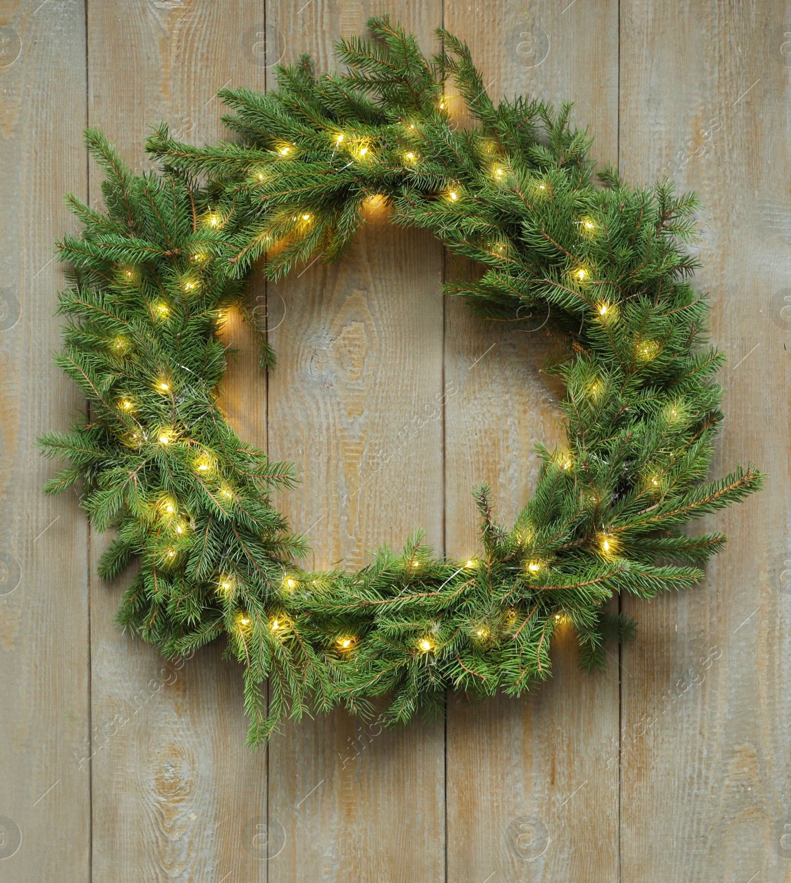 Photo of Beautiful Christmas wreath with festive lights on wooden background, top view