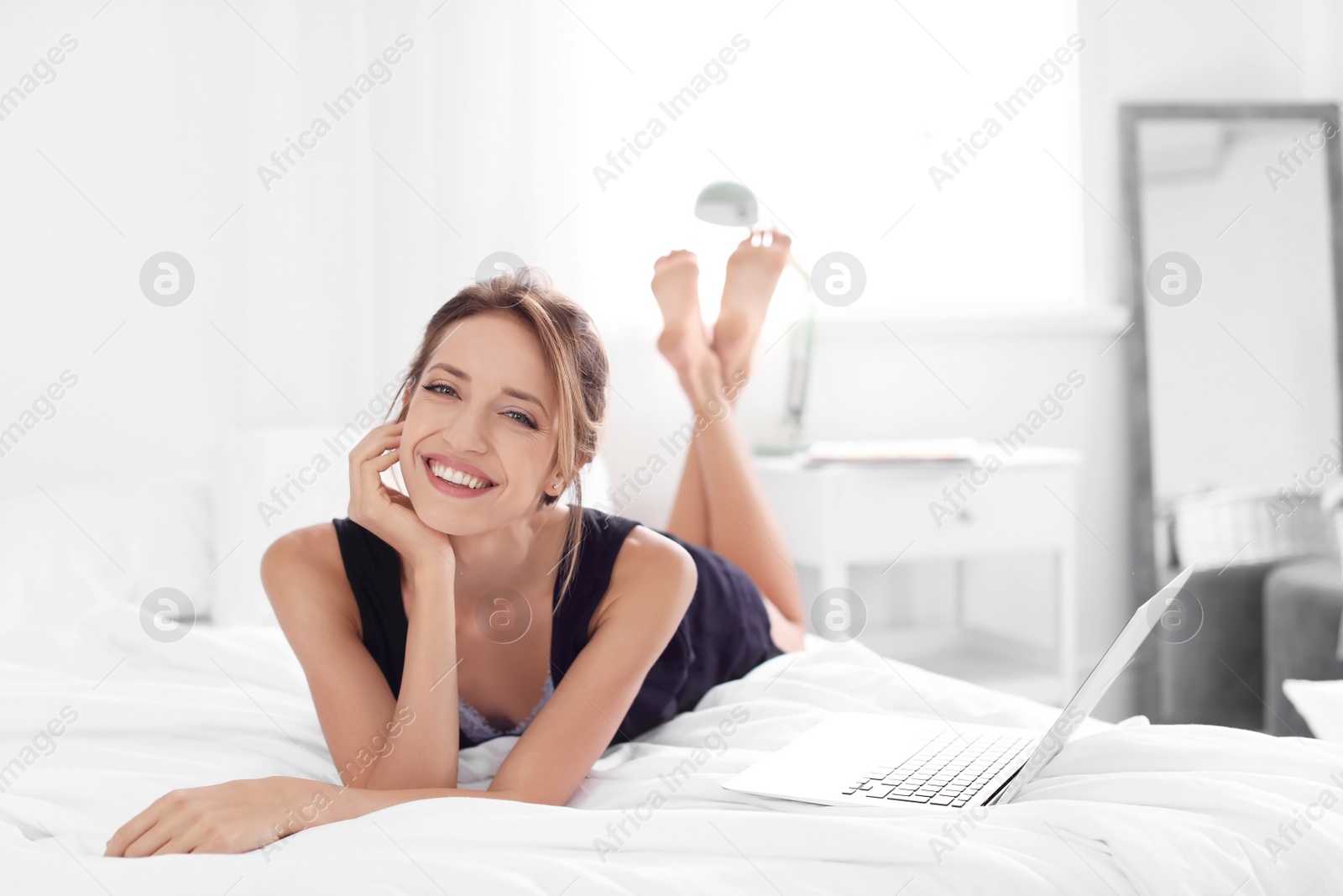 Photo of Young happy woman lying on bed at home. Lazy morning