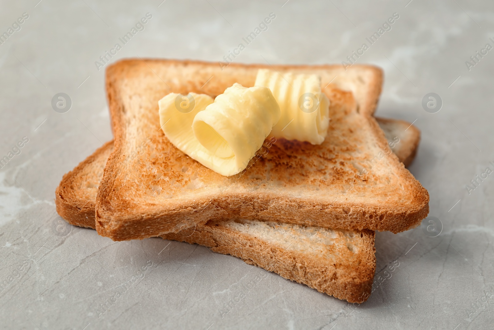 Photo of Toasted bread with butter curls on table