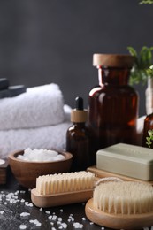 Photo of Spa composition. Brushes, soap bar and sea salt on black table