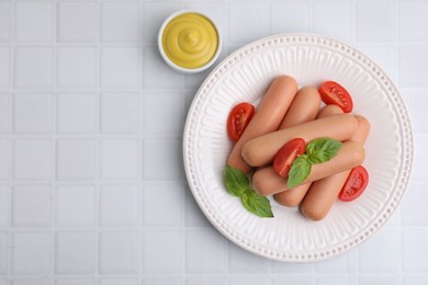 Delicious boiled sausages with tomatoes, basil and sauce on white tiled table, top view. Space for text