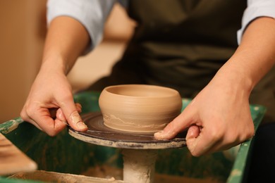 Photo of Clay crafting. Woman removing bowl from potter's wheel with thread