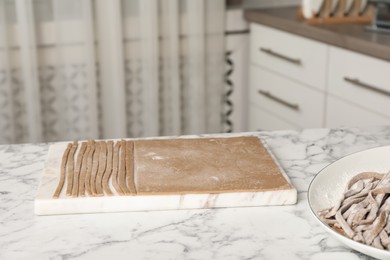 Photo of Making homemade soba (buckwheat noodles) on white marble table in kitchen