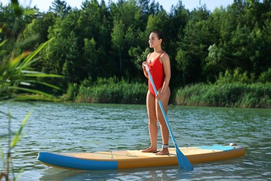Woman paddle boarding on SUP board in river