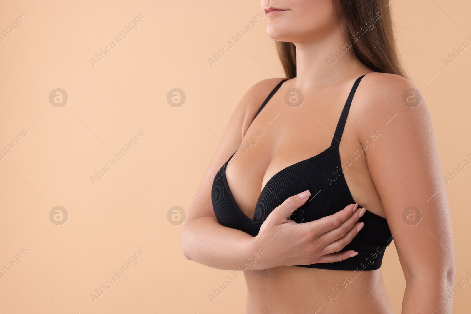 Photo of Woman with beautiful breast on beige background, closeup. Space for text