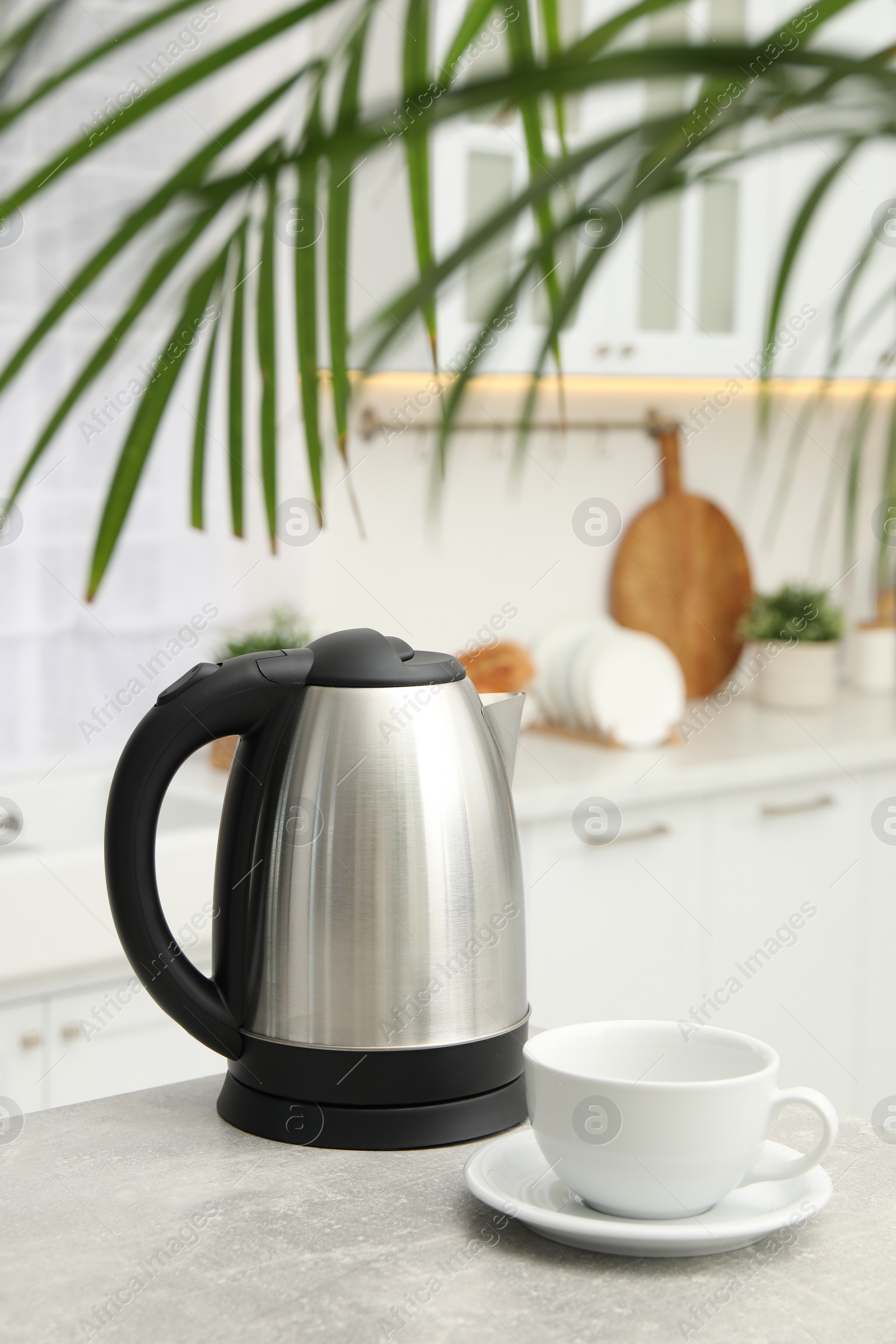 Photo of Electric kettle and cup on table in kitchen