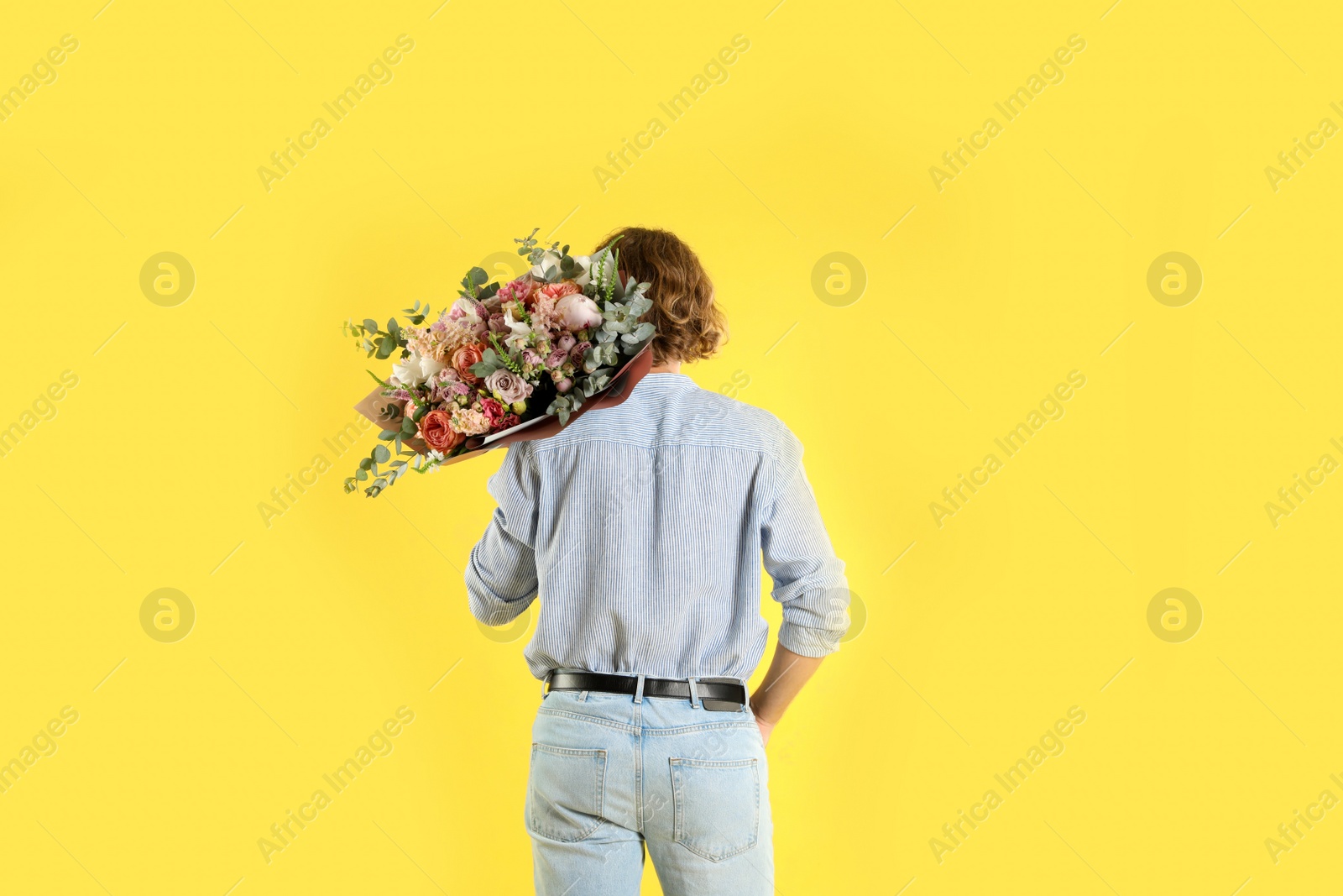 Photo of Man holding beautiful flower bouquet on yellow background