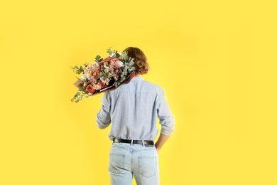 Photo of Man holding beautiful flower bouquet on yellow background