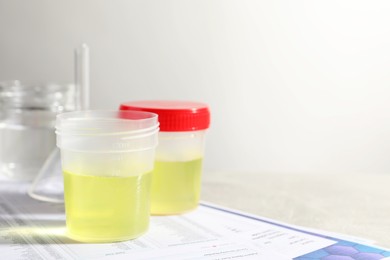 Photo of Containers with urine samples for analysis and glassware on test forms against grey background, space for text