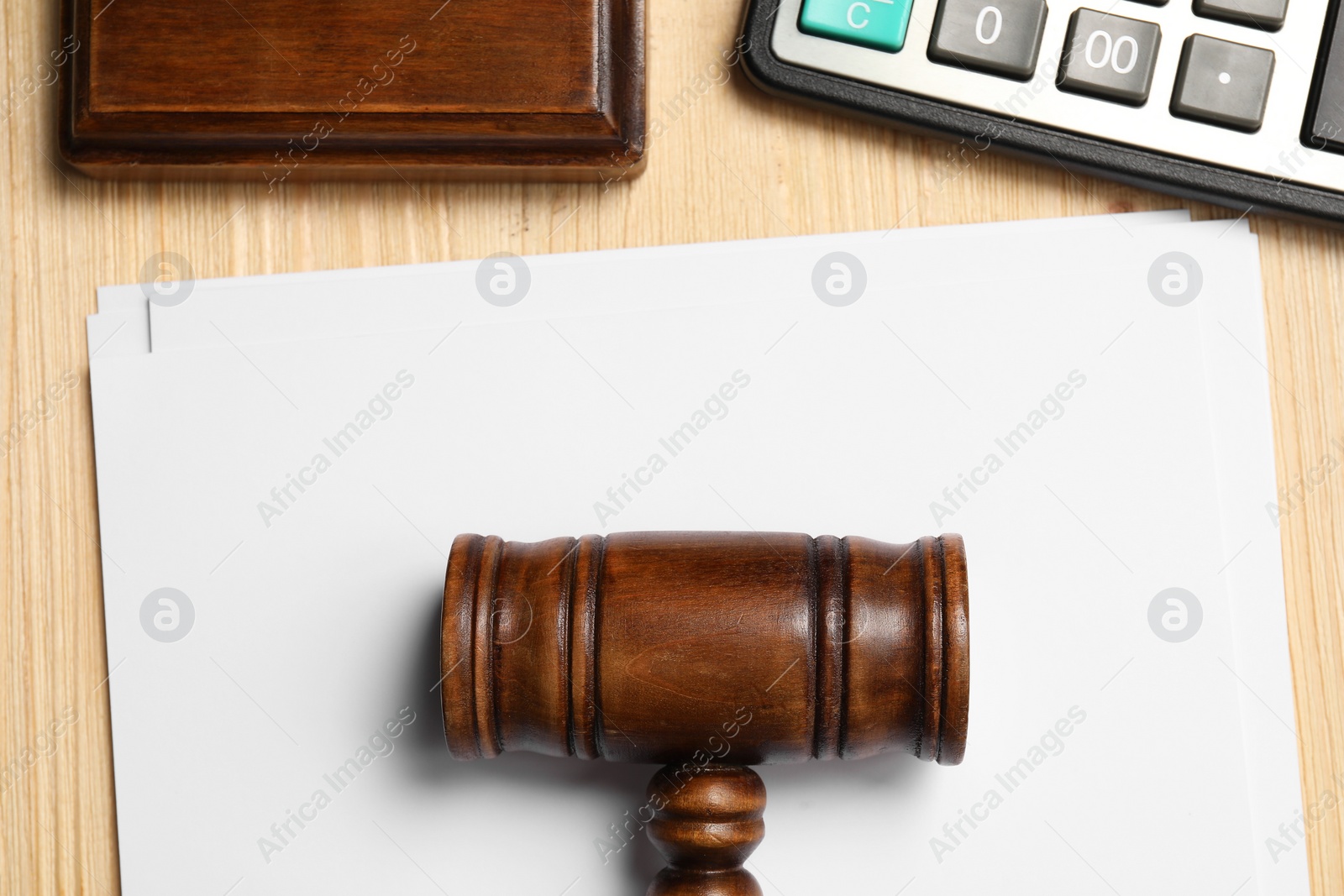 Photo of Tax law. Paper sheets, gavel and calculator on wooden table, flat lay