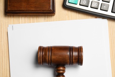 Photo of Tax law. Paper sheets, gavel and calculator on wooden table, flat lay