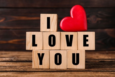 Photo of Cubes with words I Love You and red heart on wooden table