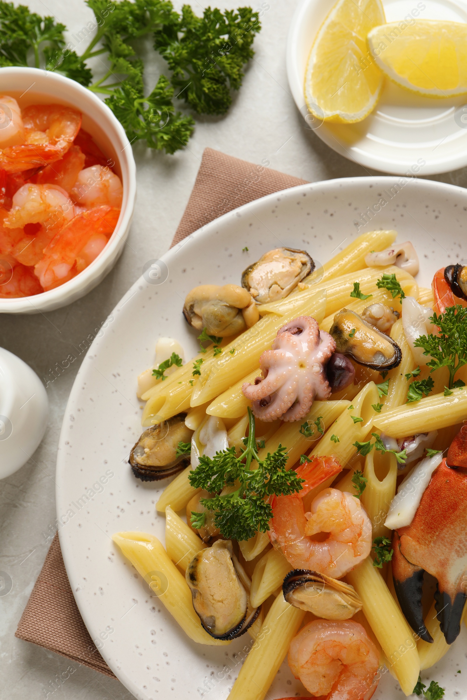 Photo of Delicious pasta with sea food and ingredients on light grey table, flat lay