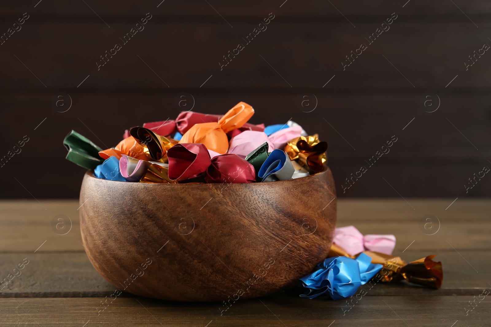 Photo of Candies in colorful wrappers on wooden table