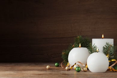 Photo of Beautiful Christmas composition with burning white candles on wooden background. Space for text