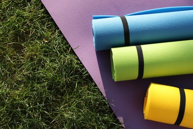 Photo of Bright exercise mats on fresh green grass outdoors, above view