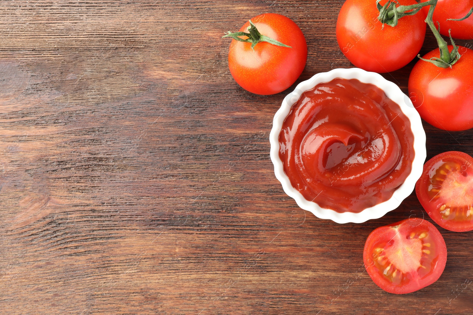 Photo of Bowl of tasty ketchup and tomatoes on wooden table, flat lay. Space for text