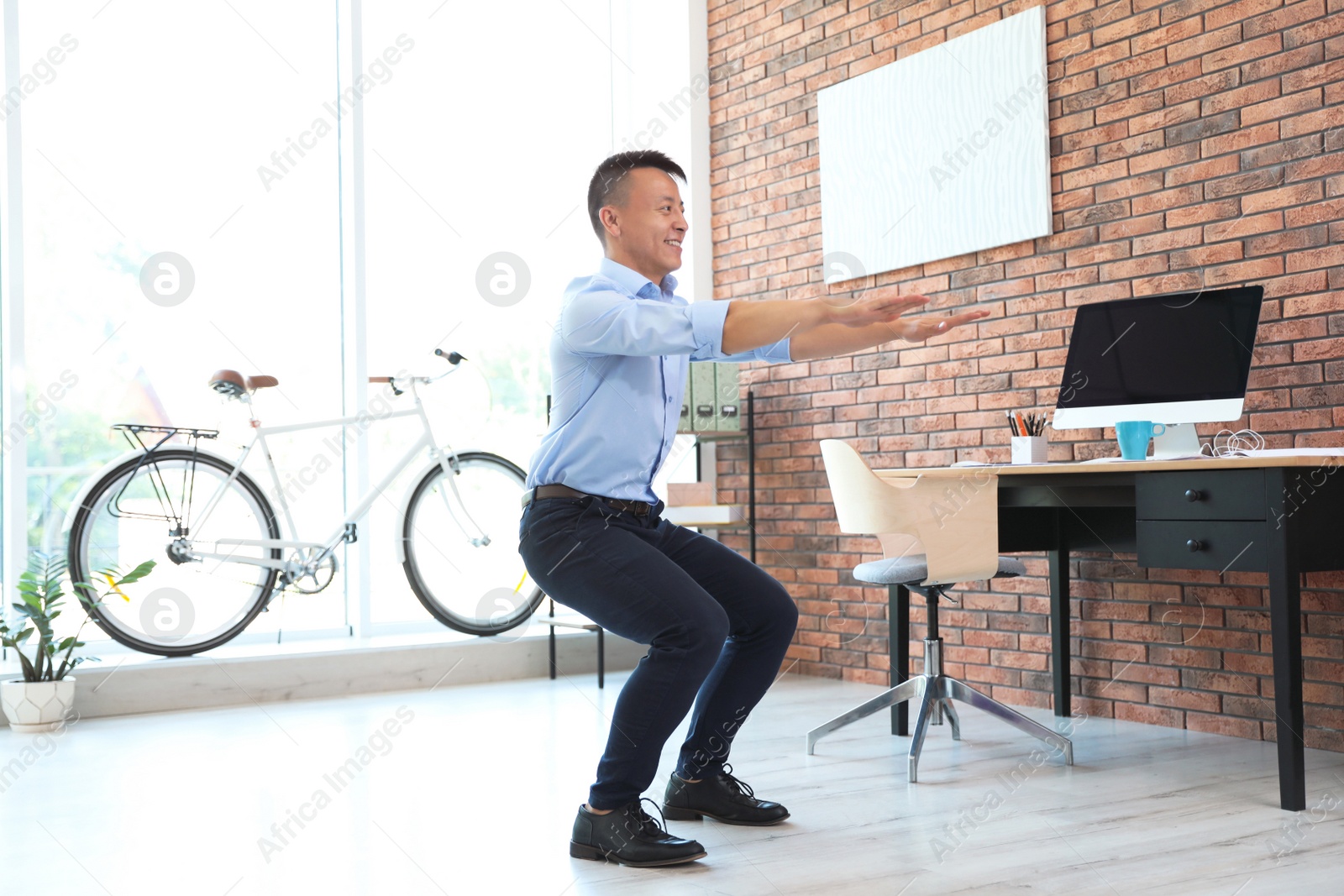 Photo of Young businessman doing exercises in office. Workplace fitness