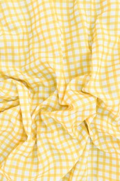 Yellow checkered picnic tablecloth as background, top view