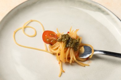Photo of Heart made with spaghetti and fork on plate, closeup