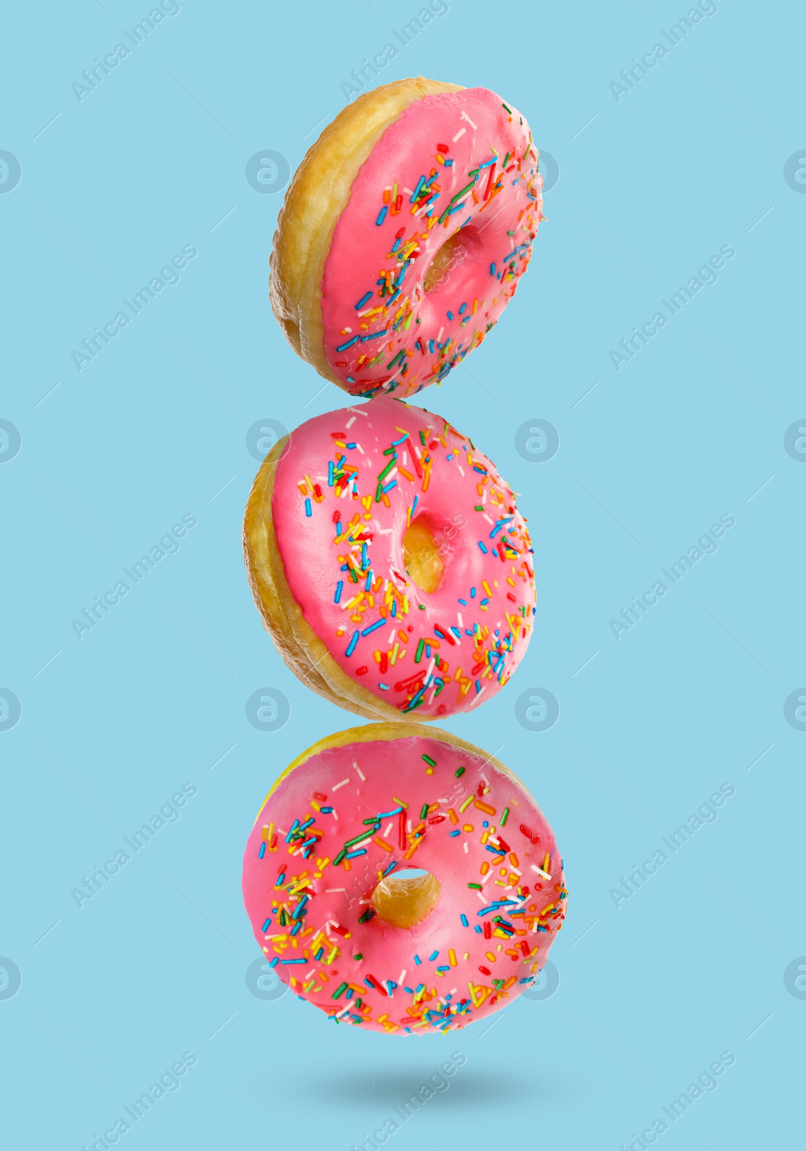 Image of Tasty donuts with sprinkles on light blue background