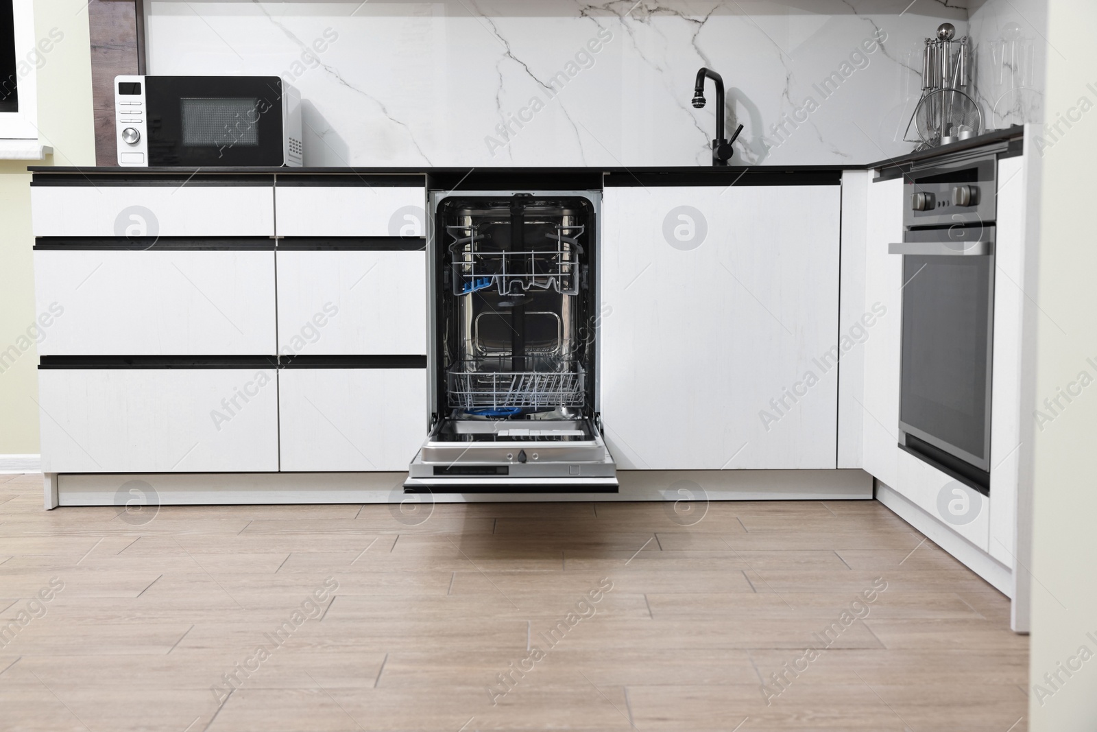 Photo of Open clean empty dishwasher in kitchen. Home appliance